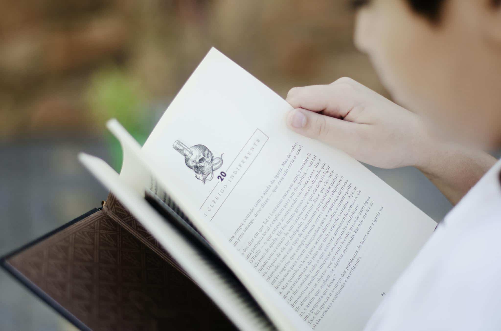 Close-up of a man reading a book outdoors, focusing on learning and relaxation.